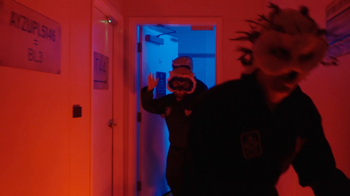 The pods are empty. Masked specimens escaping down a red-lit corridor