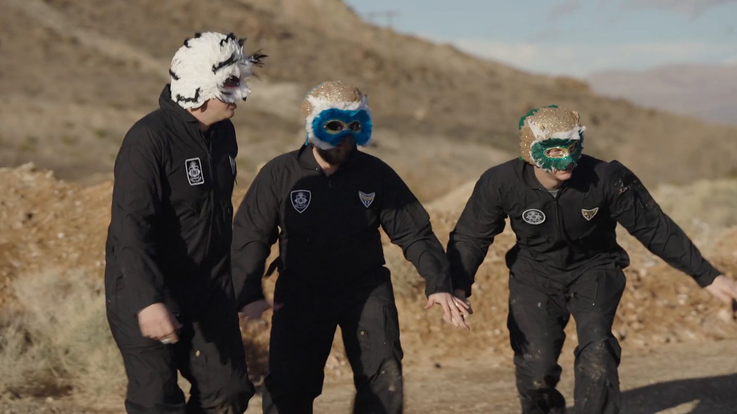 Three masked specimens walking free across the desert